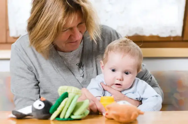 Babcia z czułością opiekuje się wnukiem, pokazując mu zabawki.