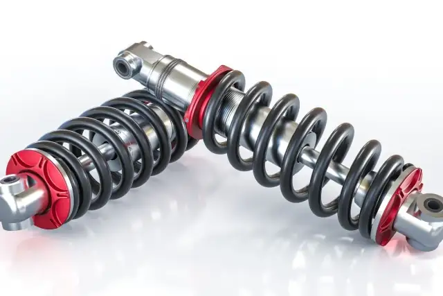 Dwa amortyzatory z czerwonymi elementami. Po wymianie amortyzatorów warto sprawdzić zbieżność, by zapewnić optymalne prowadzenie pojazdu.