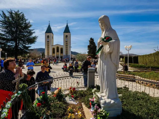Pielgrzymi w Medziugorie modlą się przed figurą Matki Bożej. Przyczyny popularności Medziugorie mimo braku oficjalnego uznania dogmatu.