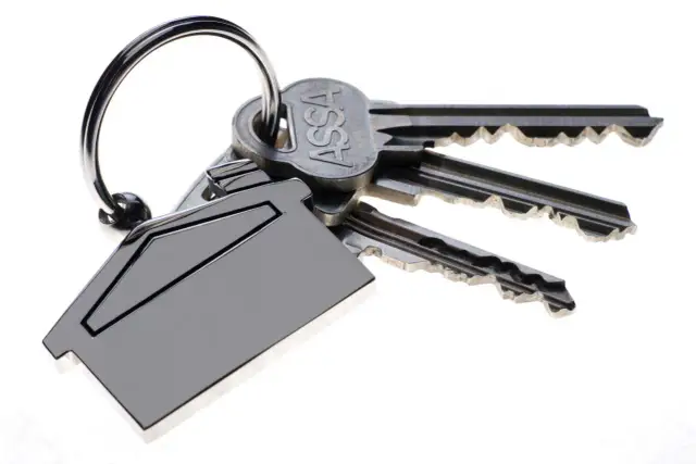 Pęk kluczy z breloczkiem w kształcie domu. Różne rodzaje kluczy do drzwi, jeden z napisem ASSA.