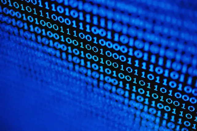 Niebieski kod binarny (0 i 1) na czarnym tle, z efektem rozmycia.