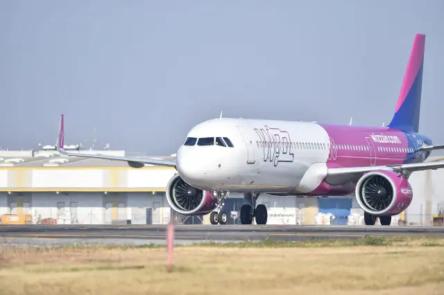 Samolot Wizzair z różowym ogonem na płycie lotniska.