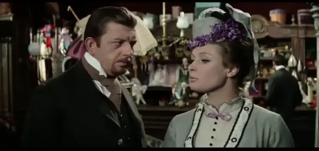 Mariusz Dmochowski w filmach, u boku pięknej kobiety w kapeluszu, w sklepie pełnym lalek i bibelotów.