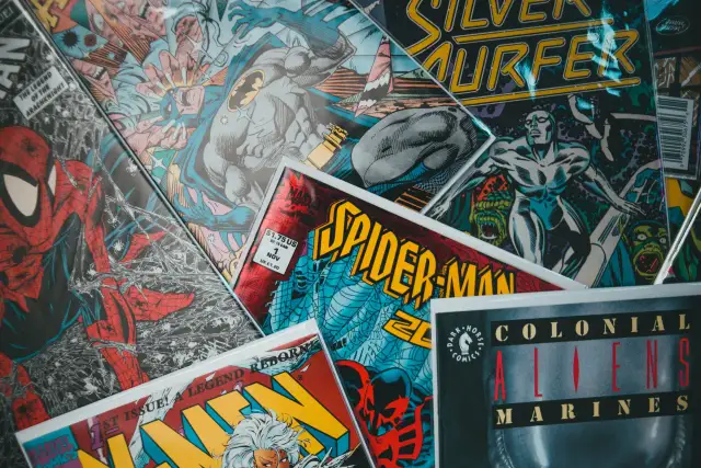Stos komiksów z postaciami takimi jak Spider-Man, Batman i Silver Surfer. Czy komiks to książka? To zależy od tego, jak na to spojrzeć!