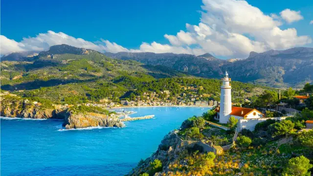 Widok na zatokę z latarnią morską, góry i miasteczko na Majorce.