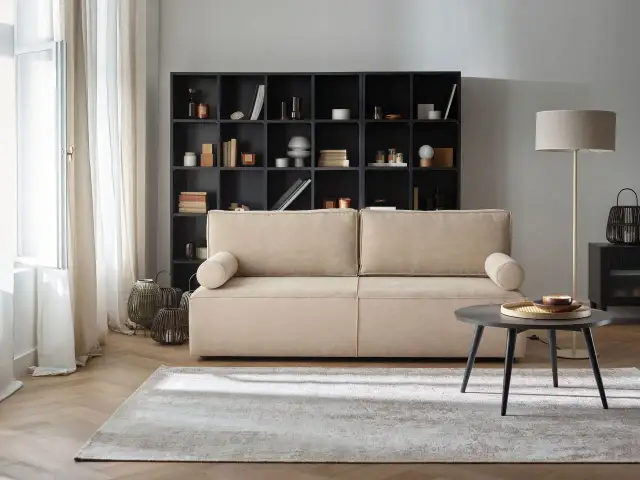 Przytulny salon z beżową kanapą i czarną biblioteczką. Gotowe aranżacje wnętrz, które inspirują do stworzenia własnej, stylowej przestrzeni.