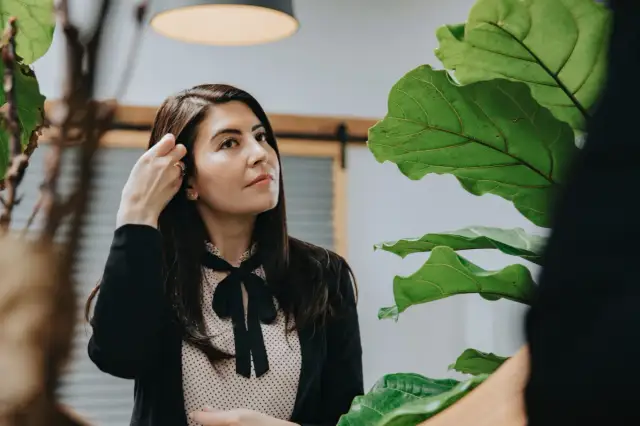 Kobieta poprawia włosy, zastanawiając się nad sobą. To gest, który może wiele mówić o psychologii i potrzebie akceptacji.