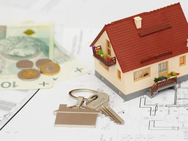 Model domu, klucze, pieniądze i plany architektoniczne.