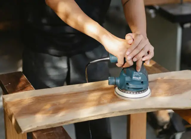 Ręce szlifują drewno szlifierką. To idealny papier ścierny do mebli, by nadać im gładkość.