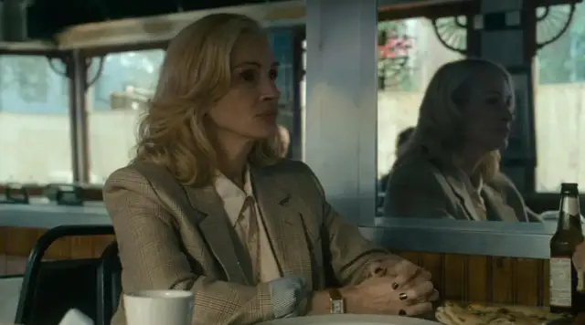 Kobieta w marynarce siedzi przy stoliku w barze, zamyślona po polowaniu.