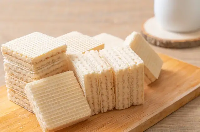 Chrupiące wafle z mlekiem w proszku i galaretką, ułożone na drewnianej desce. Idealne na deser.