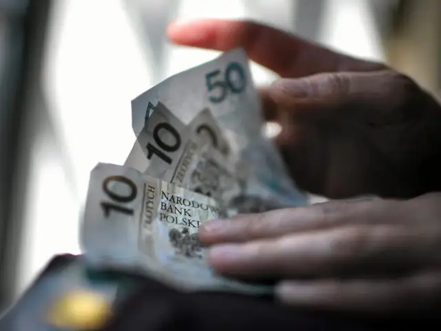 Dłoń trzyma banknoty 10 i 50 zł. Może to prezent od chrzestnej na bierzmowanie.