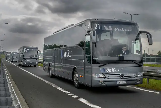 Szary bus UniBus z numerem 21 jedzie autostradą. To jeden z wielu pojazdów na trasie Kraków-Katowice.