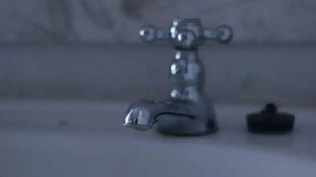 Chromowany kran w łazience, obok korek. Dowiedz się, jak wymienić wylewkę w kranie, by naprawić cieknącą baterię.