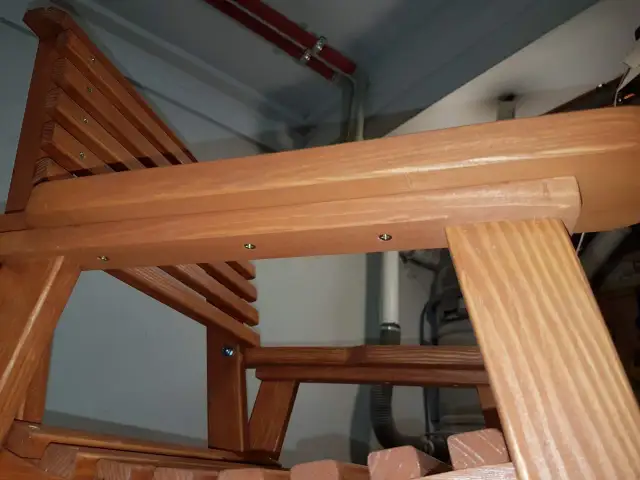 Zbliżenie na drewniane krzesło ogrodowe z widocznymi elementami konstrukcyjnymi i śrubami.