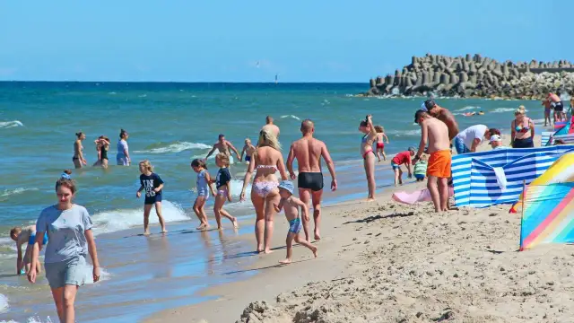 Ludzie odpoczywają na plaży nad Bałtykiem w słoneczny dzień.