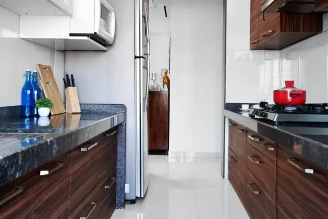 Nowoczesna kuchnia z ciemnymi szafkami, blatem i czerwonym garnkiem na kuchence.