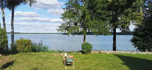 Osoba odpoczywa nad jeziorem, ciesząc się spokojem. To jedno z tych magicznych miejsc Kujawsko-Pomorskiego, gdzie czas płynie wolniej.