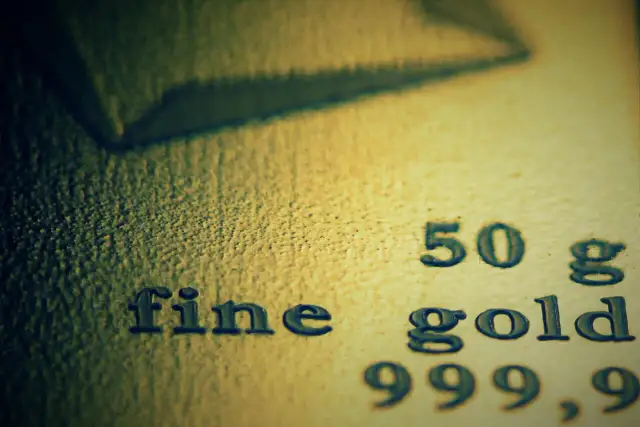 Zbliżenie na tekst "fine gold 50 g 999,9" wybity na powierzchni złota.