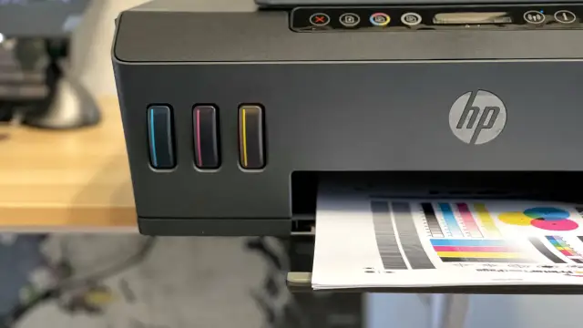 Drukarka HP z kolorowymi wskaźnikami tuszu, drukująca stronę testową. Dowiedz się, jak wydrukować z telefonu na drukarce HP.