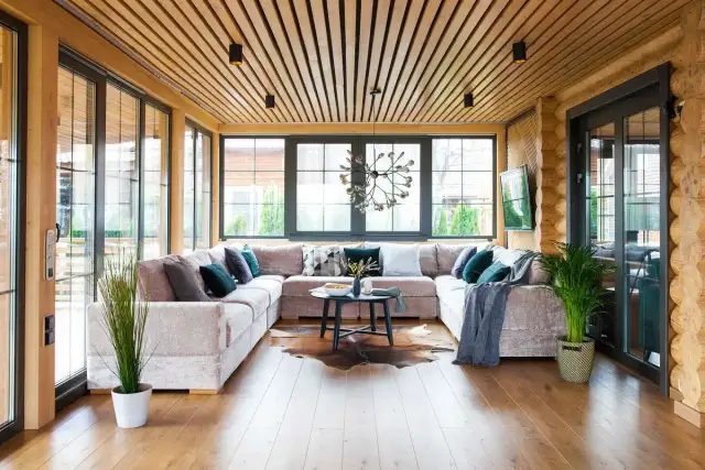 Przytulny salon z narożną sofą i imponującym, drewnianym sufitem.