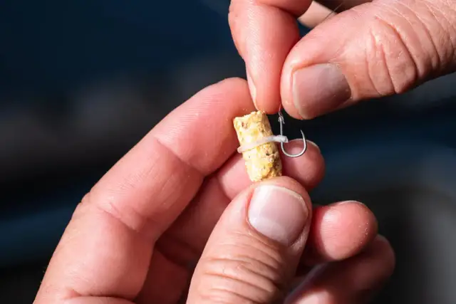 Dłonie pokazują, jak zawiązać haczyk z łopatką na przynęcie.