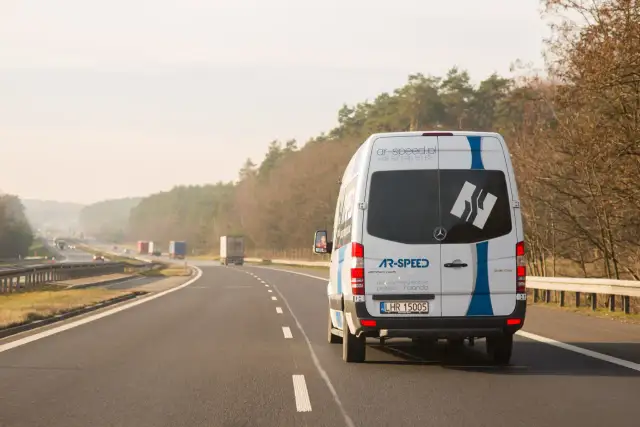 Biały bus AR-SPEED jedzie autostradą. Zastanawiasz się, ile kosztuje bus do Niemiec? Sprawdź na ar-speed.pl.