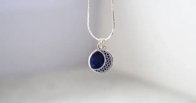 Srebrny naszyjnik z zawieszką w kształcie półksiężyca z lapis lazuli i gwiazdkami.