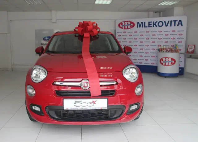 Czerwony Fiat 500X z wielką czerwoną kokardą, gotowy do wręczenia jako nagroda w loterii promocyjnej Vitay.