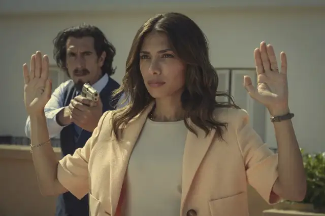 Erin Carter z podniesionymi rękami, z mężczyzną z pistoletem za nią.