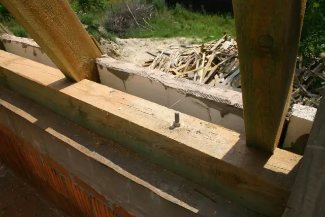 Drewniane belki konstrukcyjne, widoczna impregnacja drewna, przygotowane do budowy dachu.