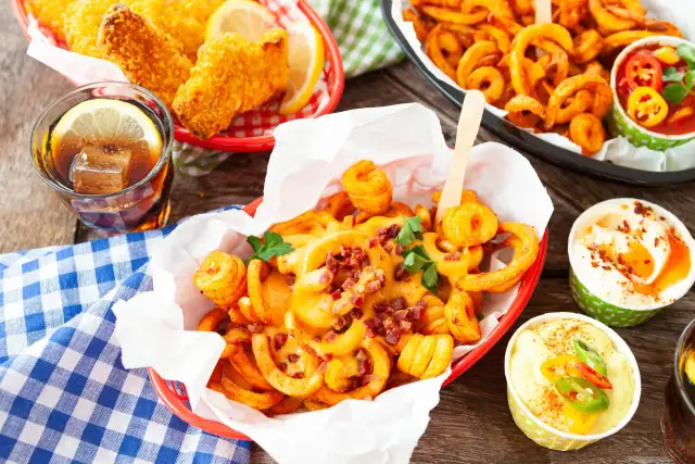 Kręcone frytki z serem i bekonem, panierowane kawałki kurczaka, napój z cytryną i sosy.