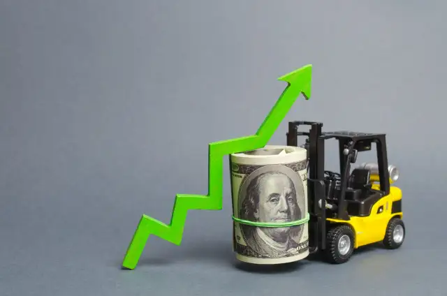 Żółty wózek widłowy podnosi zwinięty banknot 100 USD, obok zielona strzałka w górę.