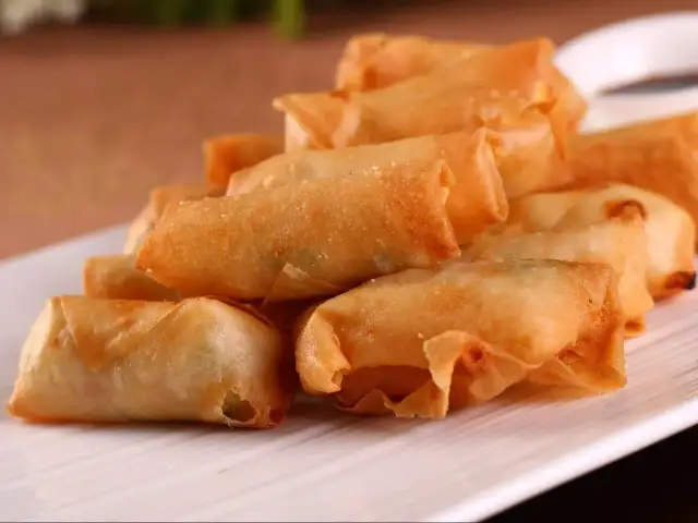 Chrupiące sajgonki z aromatycznym farszem, ułożone na białym talerzu.