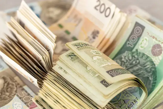 Stosy polskich banknotów 100 zł i 200 zł. Zastanawiasz się, czy wypłacać pieniądze z banku?