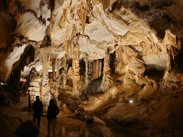 Odkrywanie najpiękniejszych jaskiń w Polsce. Dwie osoby podziwiają imponujące stalaktyty i stalagmity w oświetlonej grocie.