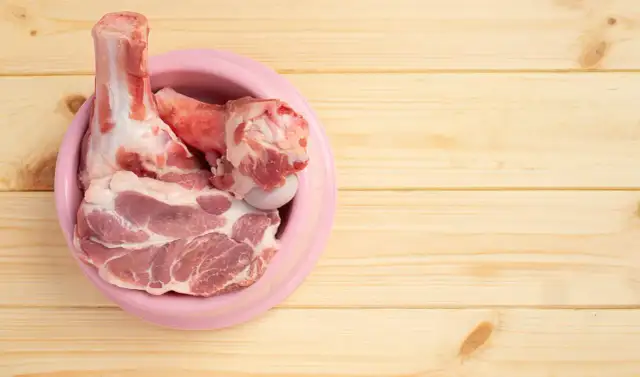 Surowe mięso i kości w różowej misce. Idealne, jakie mięso dla szczeniaka na początek przygody z BARF.