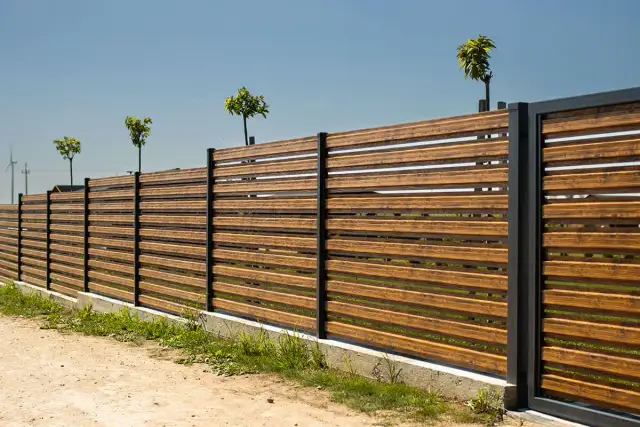Nowoczesne, drewniane ogrodzenie z czarnymi słupkami. Ciekawe ogrodzenia galeria inspiracji.