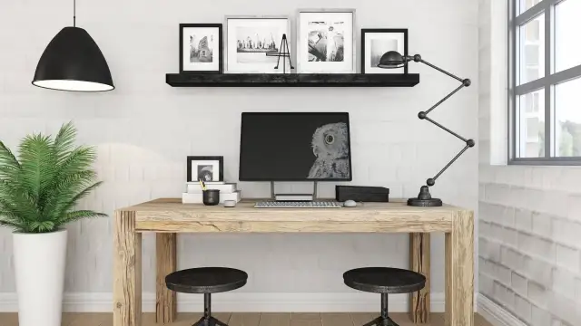 Przytulne biuro z drewnianym biurkiem, monitorem z sową, lampą i rośliną.