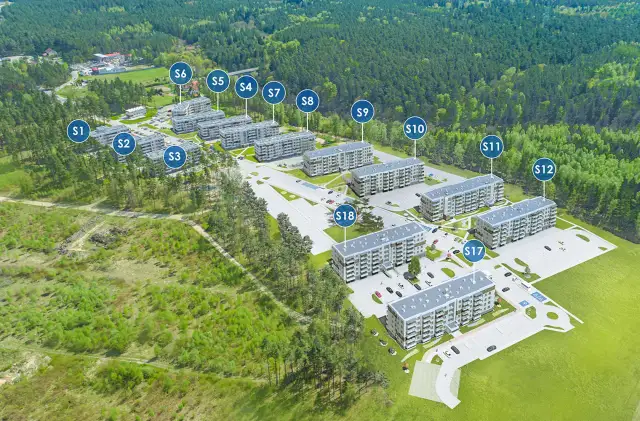 Widok z lotu ptaka na osiedle budynków mieszkalnych otoczone lasem, z oznaczeniami budynków.