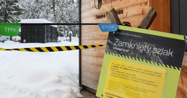 Tablica informacyjna "Zamknięty szlak" w Tatrach zimą, z taśmą ostrzegawczą.