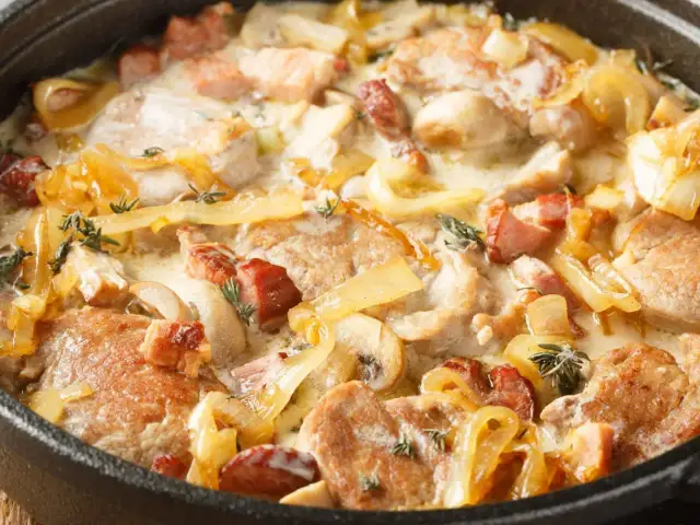 Polędwiczka wieprzowa w sosie śmietanowym z cebulą i boczkiem w naczyniu żeliwnym.