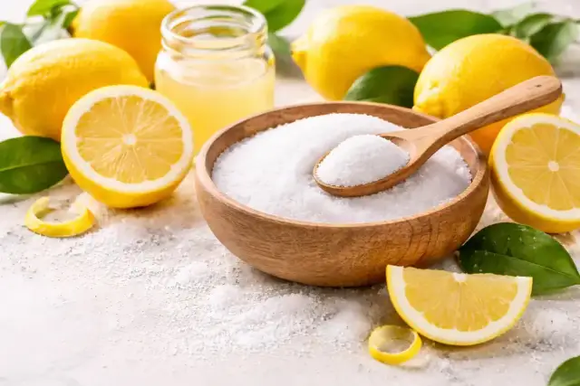 Składniki do domowych kosmetyków: cytryny, sok z cytryny i biały proszek, który jest kluczowy jako citric acid w kosmetykach.