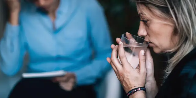 Kobieta pije wodę podczas terapii.