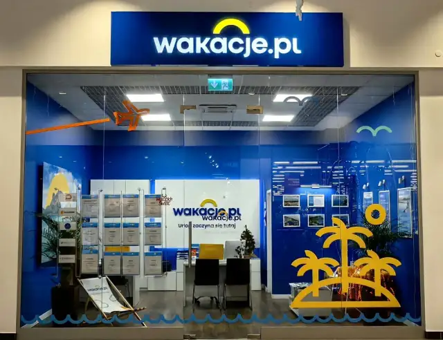 Witryna biura podróży Wakacje.pl z logo, wystawami ofert i dekoracjami wakacyjnymi.