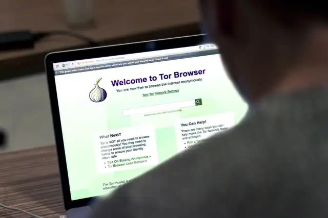 Osoba korzysta z laptopa z otwartą stroną powitalną przeglądarki **Tor Browser**, która umożliwia anonimowe przeglądanie Internetu.