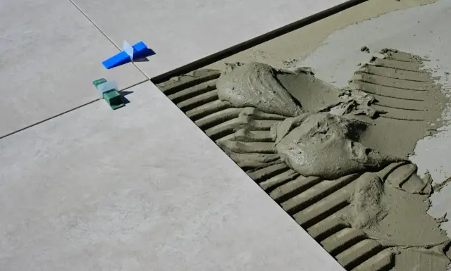 Płytki ceramiczne układane na kleju, widoczne kliny dystansowe i precyzyjnie określona szerokość fugi.