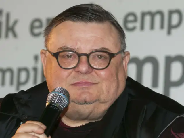 Wojciech Mann, znany z audycji radiowych, w okularach i z mikrofonem. Jego wiek nie jest widoczny na zdjęciu.