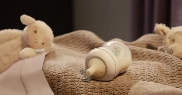 Butelka Avent z mlekiem i pluszowe owieczki na kocyku.