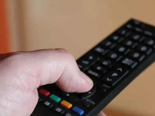 Dłoń trzymająca pilot do telewizora Samsung, naciskająca przyciski.